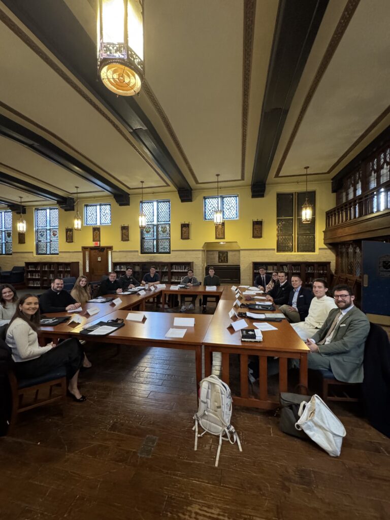 15 men and women sitting around a table after participating in a seminar contemplating the connection between morals and religion. 